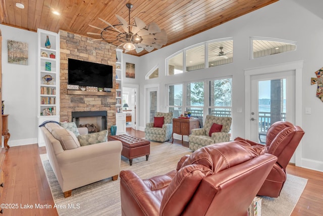 living room with light hardwood / wood-style flooring, wood ceiling, a fireplace, and ceiling fan