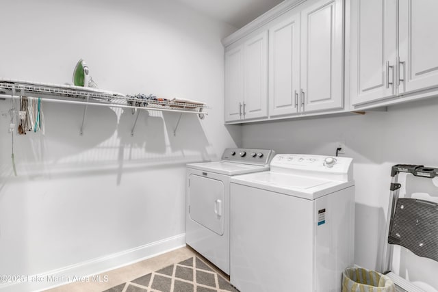 washroom featuring cabinets and washer and clothes dryer