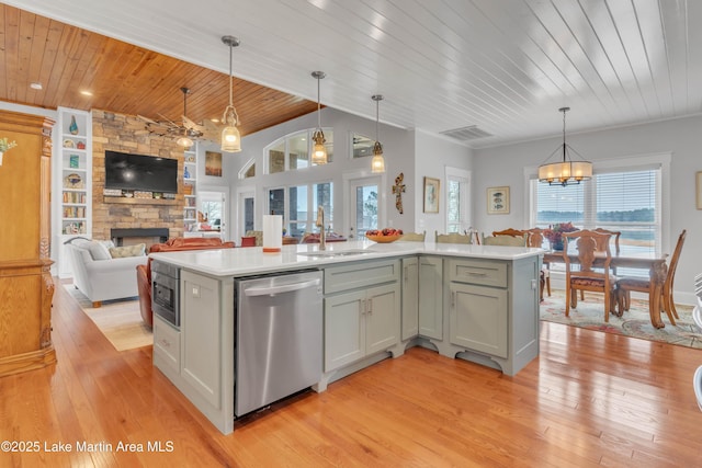 kitchen featuring sink, decorative light fixtures, stainless steel appliances, and an island with sink