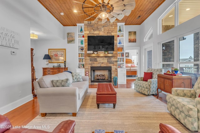 living room featuring crown molding, a fireplace, wooden ceiling, and light wood-type flooring