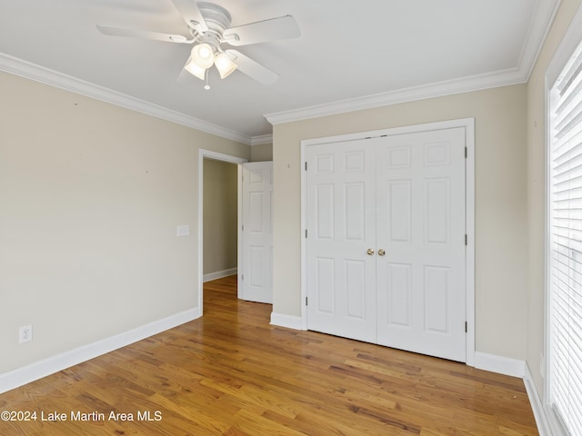 unfurnished bedroom featuring hardwood / wood-style floors, ceiling fan, crown molding, and a closet