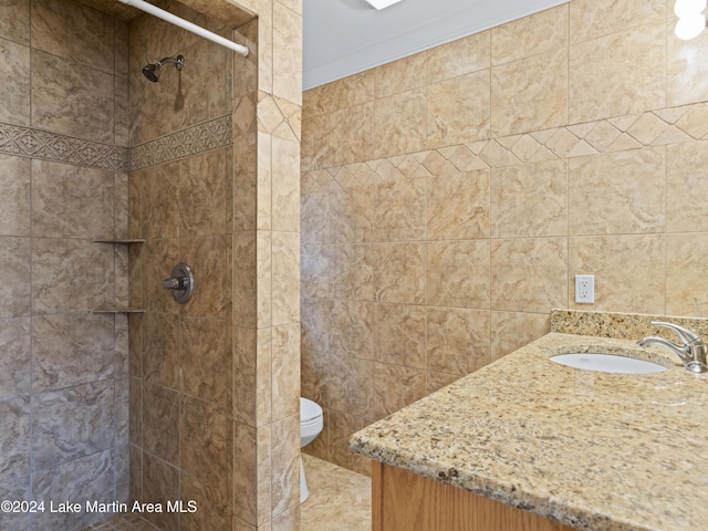 bathroom with a tile shower, sink, ornamental molding, and toilet