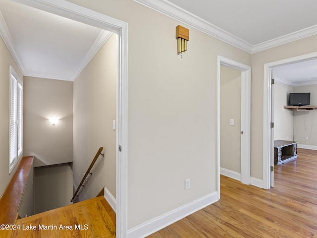 hallway with light hardwood / wood-style flooring and crown molding