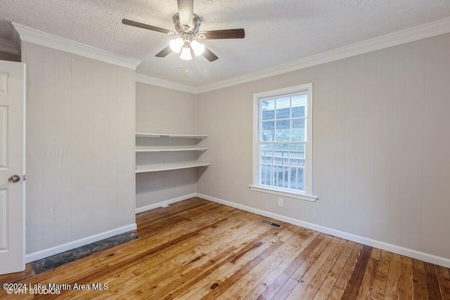 empty room with ceiling fan, wood-type flooring, a textured ceiling, and ornamental molding