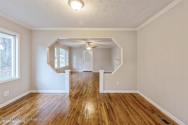 unfurnished room featuring ceiling fan, wood-type flooring, a textured ceiling, and ornamental molding