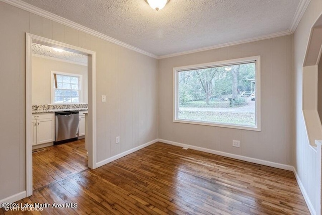 empty room featuring wood-type flooring, a textured ceiling, and ornamental molding