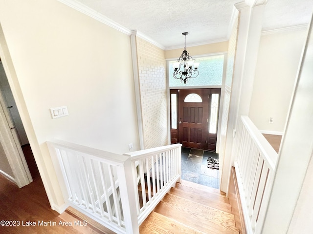 foyer entrance with a notable chandelier, crown molding, and light hardwood / wood-style flooring