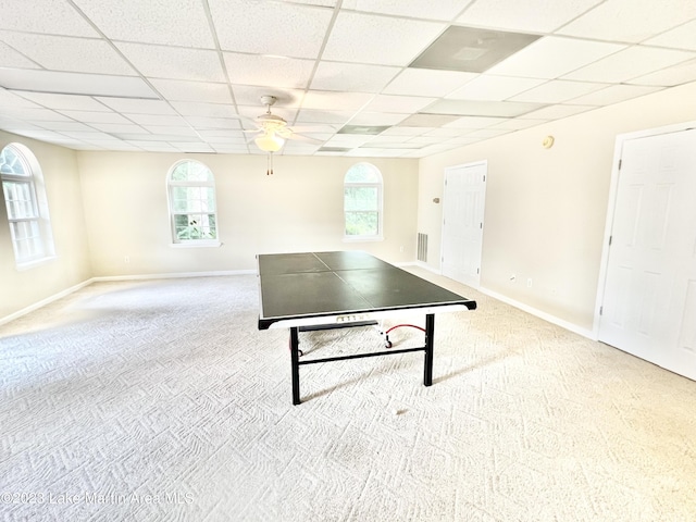 rec room with a paneled ceiling, a healthy amount of sunlight, and light carpet