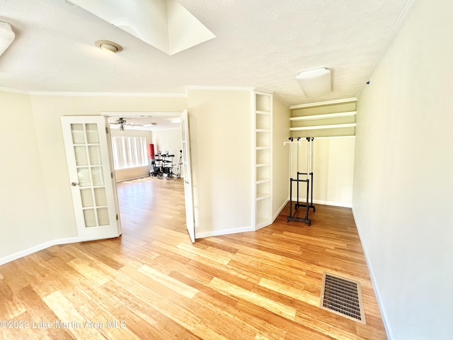 hallway featuring wood-type flooring, a textured ceiling, and ornamental molding