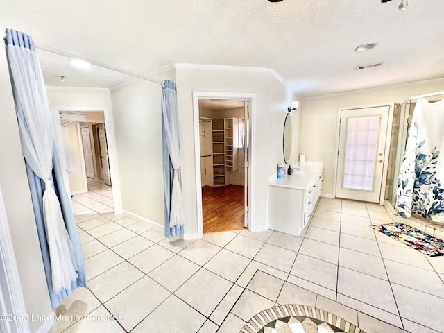 bathroom featuring a textured ceiling, vanity, tile patterned floors, and ornamental molding