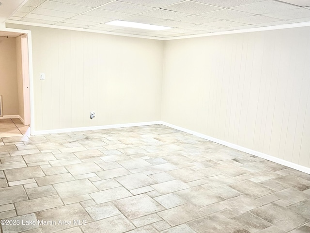 empty room with a paneled ceiling and wooden walls