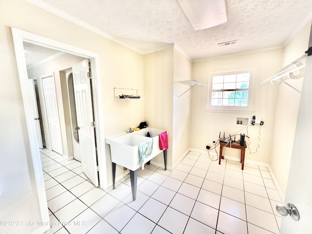 washroom with hookup for a washing machine, light tile patterned floors, a textured ceiling, and ornamental molding