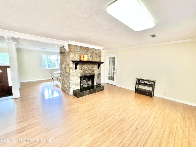 unfurnished living room with hardwood / wood-style flooring, a stone fireplace, ornamental molding, and a textured ceiling