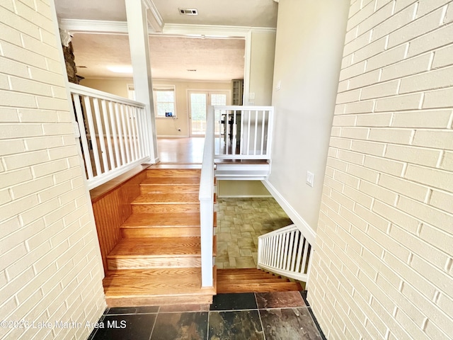 stairs featuring ornamental molding and brick wall