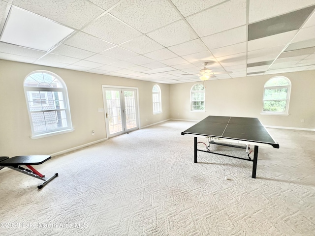 rec room featuring a paneled ceiling, ceiling fan, light colored carpet, and french doors