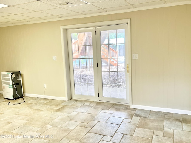 doorway featuring a paneled ceiling and wood walls