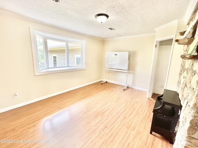 spare room with crown molding, light wood-type flooring, and a textured ceiling