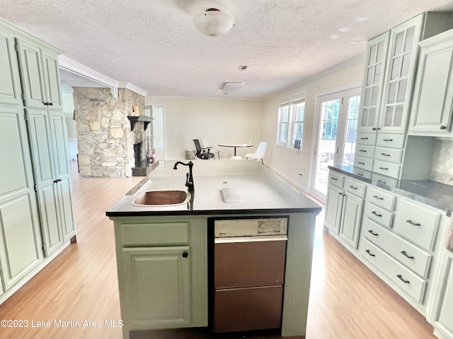 kitchen with sink, green cabinets, a textured ceiling, a fireplace, and light wood-type flooring