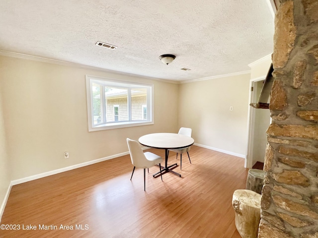 dining space with crown molding, a textured ceiling, and hardwood / wood-style flooring