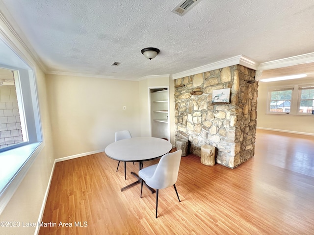 dining room with a fireplace, hardwood / wood-style floors, a textured ceiling, and crown molding