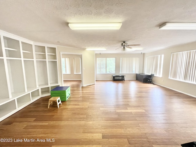 interior space with a textured ceiling, light wood-type flooring, and ceiling fan