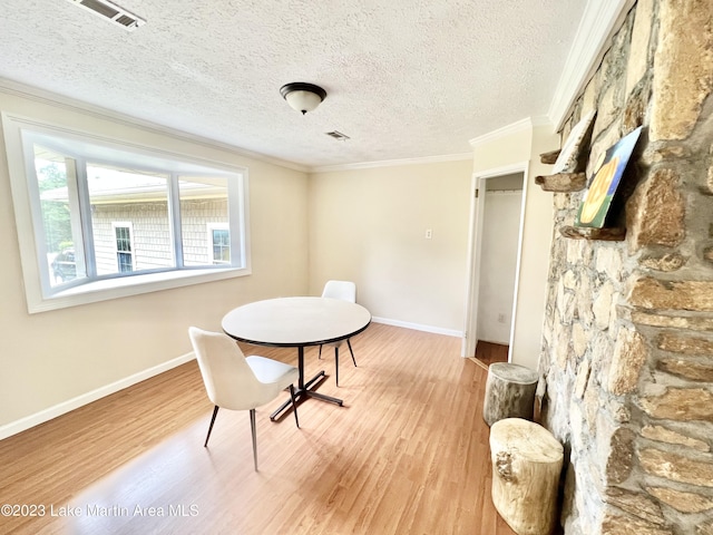 dining space with a textured ceiling, hardwood / wood-style flooring, and ornamental molding