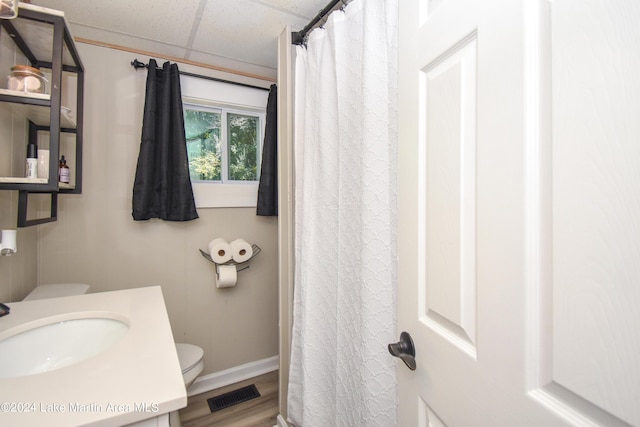 bathroom featuring vanity, hardwood / wood-style floors, a paneled ceiling, and toilet