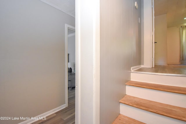 stairway with wooden walls, hardwood / wood-style flooring, and ornamental molding