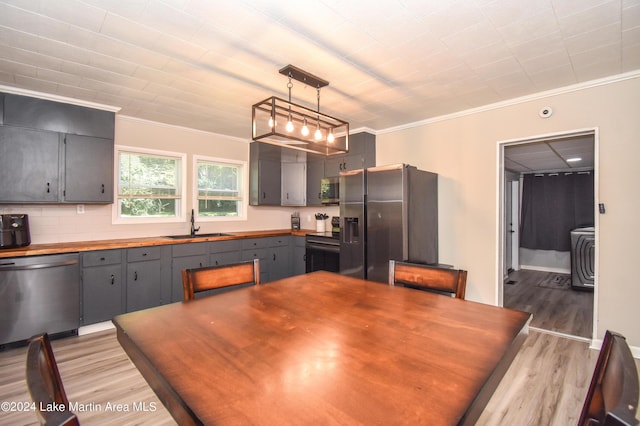 kitchen with crown molding, hanging light fixtures, light wood-type flooring, and appliances with stainless steel finishes