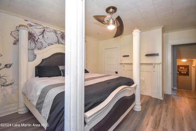 bedroom with dark hardwood / wood-style flooring, ceiling fan, and ornamental molding