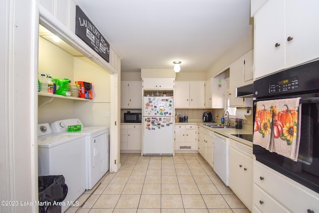 kitchen featuring sink, washing machine and dryer, white cabinets, light tile patterned flooring, and black appliances