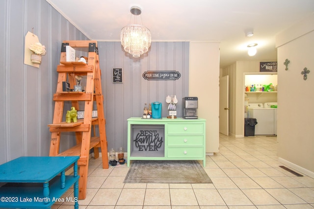 interior space with hanging light fixtures, independent washer and dryer, wood walls, a chandelier, and light tile patterned flooring