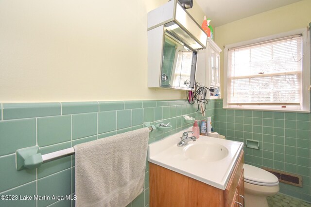 bathroom featuring vanity, toilet, and tile walls