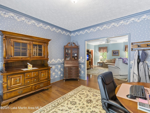 home office with wallpapered walls, a textured ceiling, wood finished floors, and baseboards