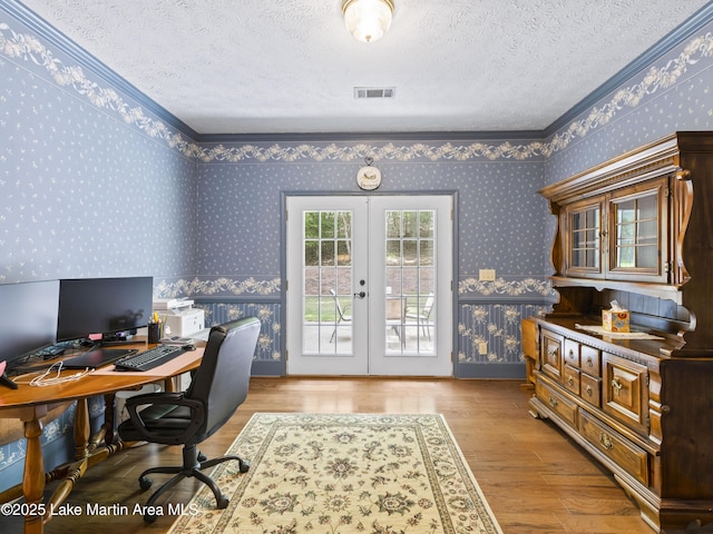 home office featuring french doors, wallpapered walls, and a textured ceiling