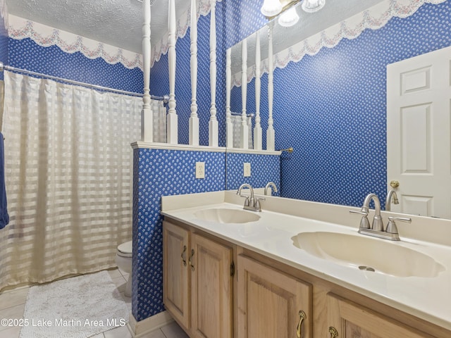 bathroom featuring wallpapered walls, a textured ceiling, and a sink