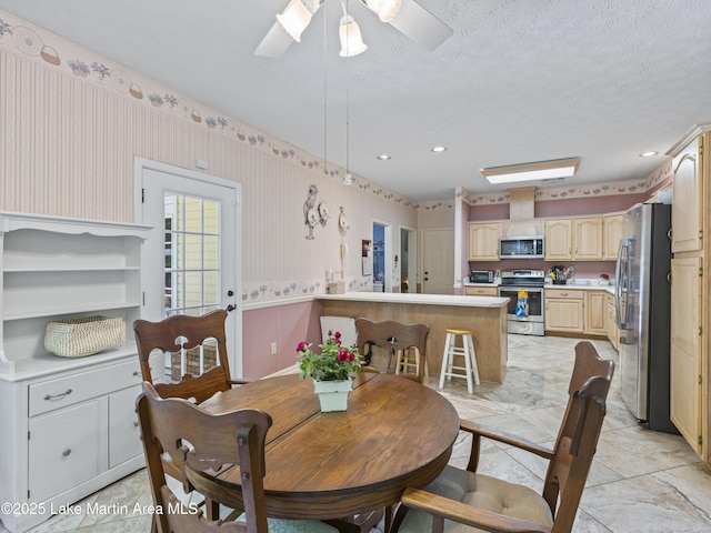 dining room with a wainscoted wall, a ceiling fan, and wallpapered walls