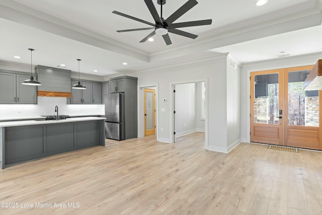 kitchen with gray cabinetry, light countertops, freestanding refrigerator, a tray ceiling, and decorative light fixtures