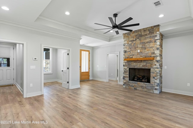 unfurnished living room featuring a tray ceiling, a fireplace, light wood-style flooring, and visible vents