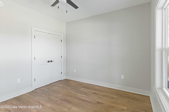 spare room featuring a ceiling fan, light wood-style flooring, and baseboards