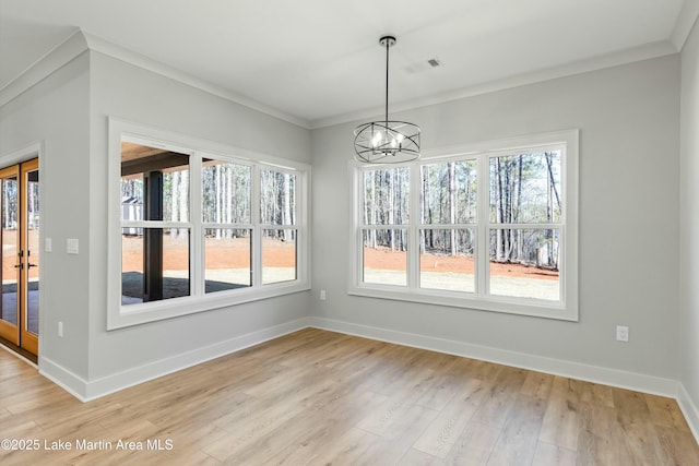 unfurnished dining area with crown molding, baseboards, wood finished floors, and a notable chandelier