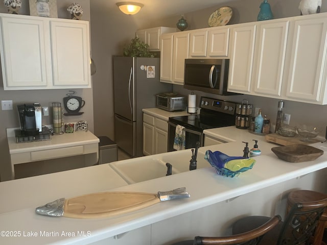 kitchen featuring white cabinetry, a kitchen bar, and appliances with stainless steel finishes