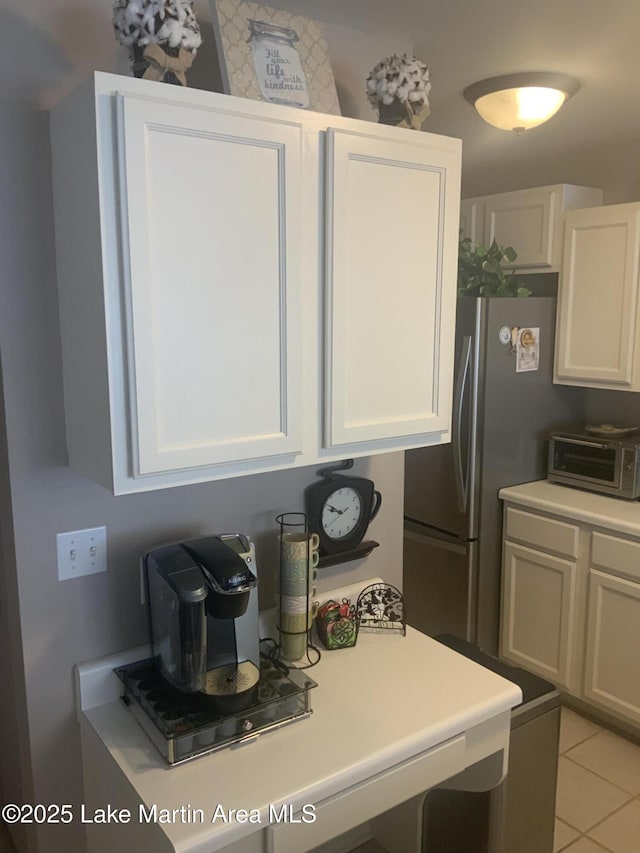 kitchen featuring light tile patterned floors, white cabinets, and stainless steel refrigerator