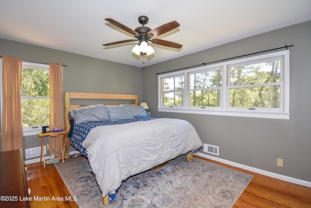 bedroom with visible vents, baseboards, a ceiling fan, and wood finished floors