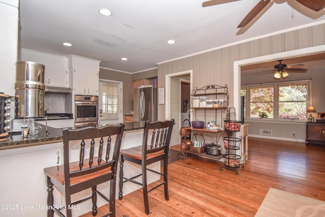 kitchen with plenty of natural light, ornamental molding, freestanding refrigerator, and a ceiling fan