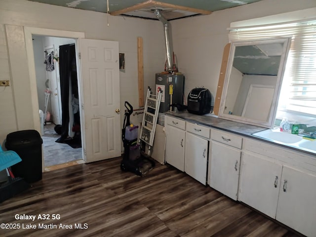 interior space featuring white cabinetry, dark countertops, water heater, and dark wood-type flooring