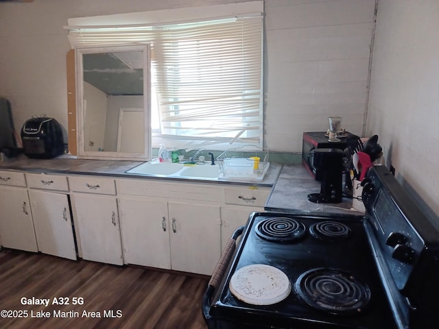 kitchen featuring dark wood-type flooring, white cabinetry, range with electric stovetop, and a sink