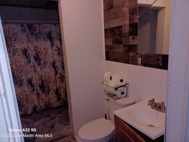 full bath with wood walls, a shower with shower curtain, toilet, and vanity