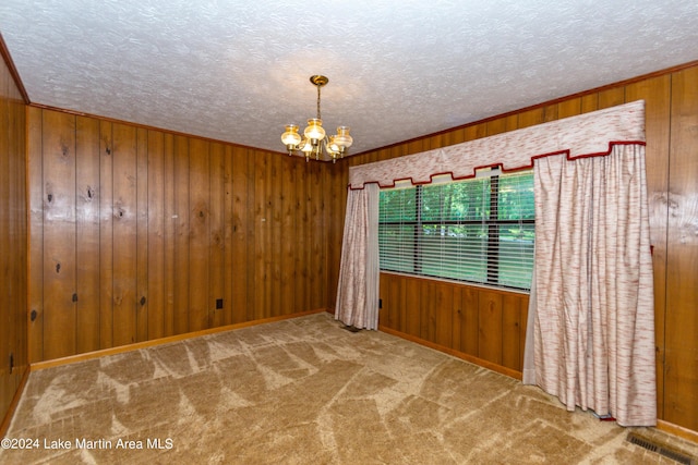 spare room featuring carpet floors, an inviting chandelier, and wooden walls