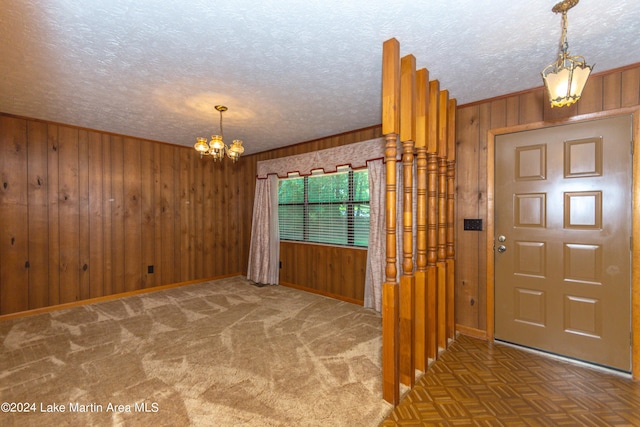 foyer featuring wood walls, parquet floors, a chandelier, and a textured ceiling